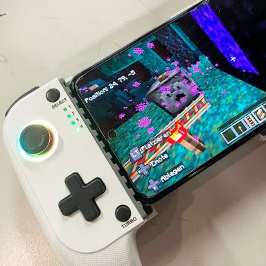 Spielkonsole mit Steuerknöpfen und Bildschirm, der ein Spiel zeigt.