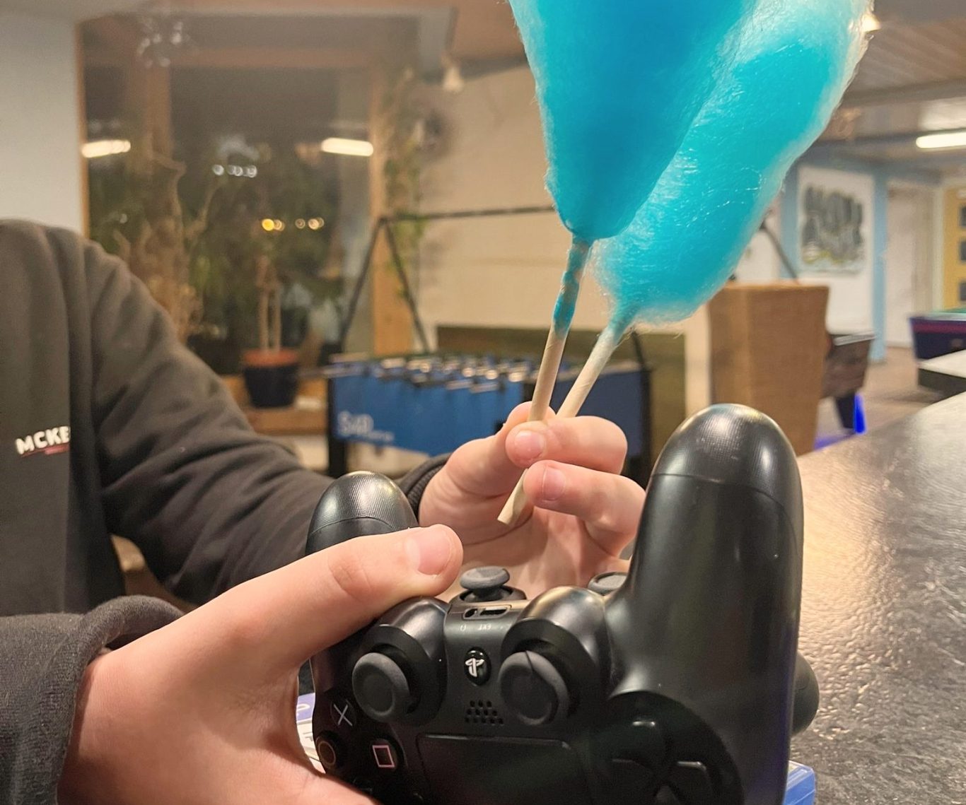 Eine Person hält einen Controller in einer Hand und Zuckerwatte in der anderen.