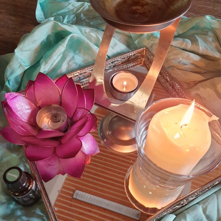 Eine arrangierte Szene mit einer Lotusblüte, Kerzen und einem Duftöl auf einem Tablett.