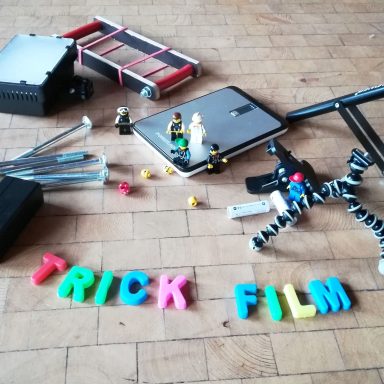 Verschiedene Objekte zum Filmemachen, darunter Figuren und bunte Buchstaben "TRICK FILM".