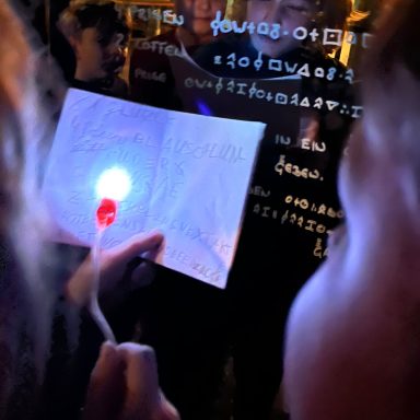 Ein Handheld-Licht wird auf ein Blatt Papier mit geheimnisvollen Zeichen gehalten.