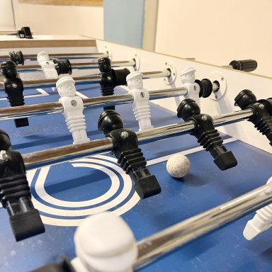 Tischfußballspiel mit schwarzen und weißen Figuren und einem weißen Ball.