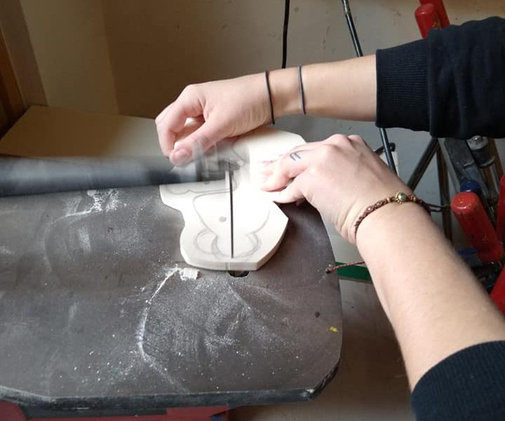 Eine Person schneidet Holz mit einer Säge auf einer Werkbank.